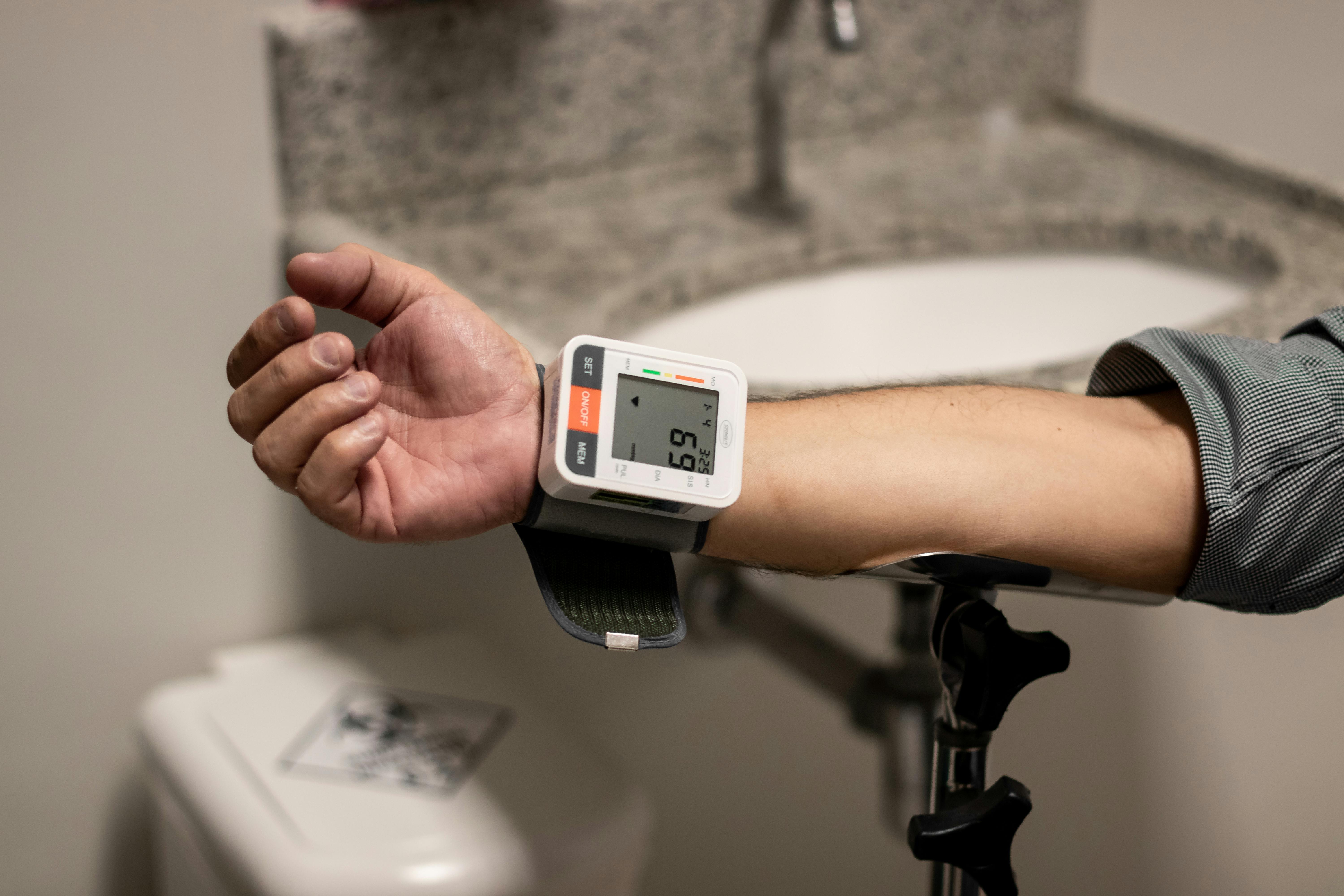 Close-up of an arm using a wrist sphygmomanometer in a healthcare setting.